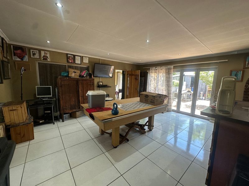 Spacious living area featuring large format floor tiles, recessed lighting, and sliding glass doors providing direct access to the outdoor area.