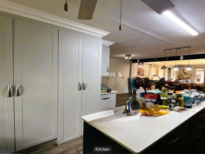 Spacious open-plan kitchen featuring a large central island, ample built-in cabinetry, and modern lighting, seamlessly flowing into the adjacent living area.