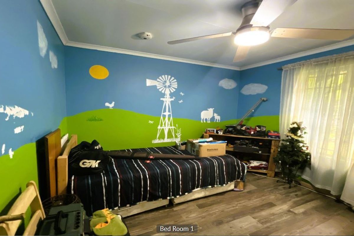 A bedroom featuring laminate flooring and a ceiling fan, currently decorated with a custom wall mural.