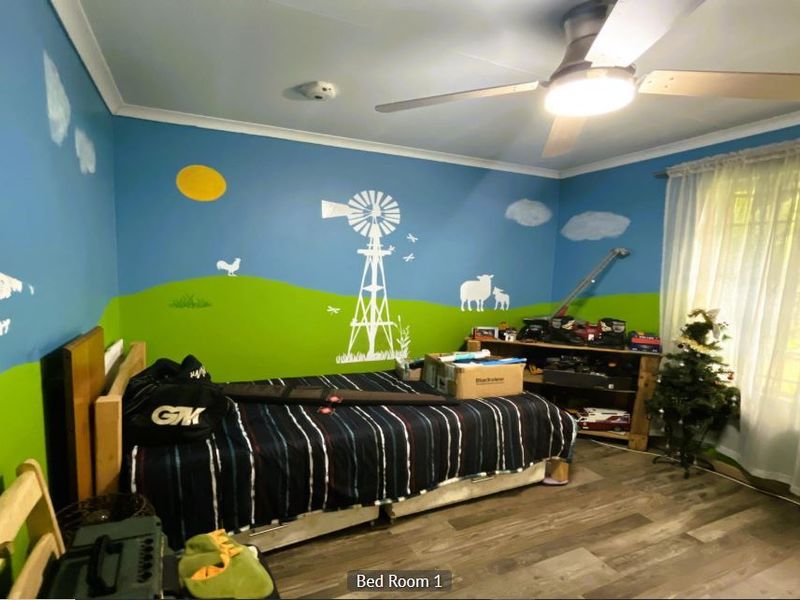 A bedroom featuring laminate flooring and a ceiling fan, currently decorated with a custom wall mural.