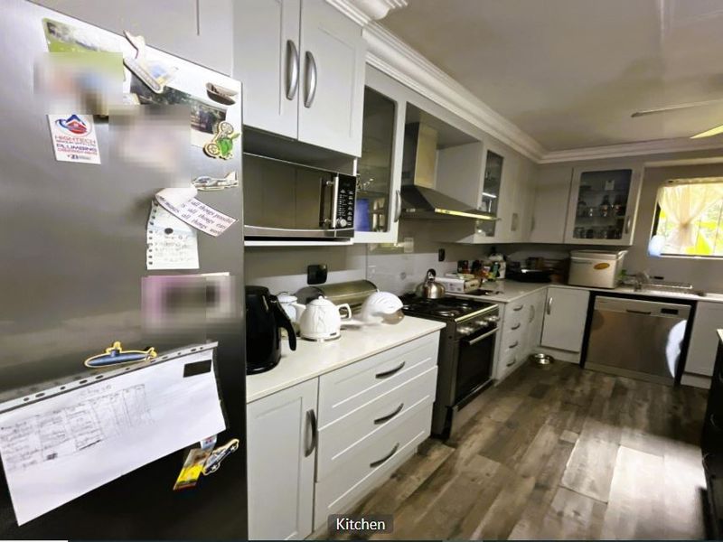 A functional kitchen featuring light grey cabinetry, integrated appliances, a gas stove with extractor fan, and durable laminate flooring.