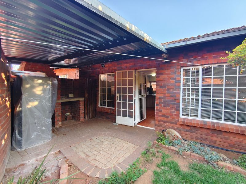 Covered outdoor patio area featuring a built-in brick braai, paved flooring, and direct access to the interior living space.