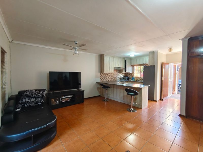 Open-plan living and kitchen area featuring tiled flooring, a breakfast bar, and built-in cabinetry, providing a functional and connected living space.