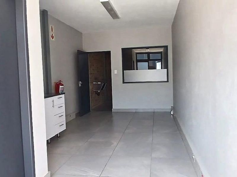 A clean, functional utility space featuring tiled flooring, built-in cabinetry, and a fire extinguisher, suitable for office or storage use.