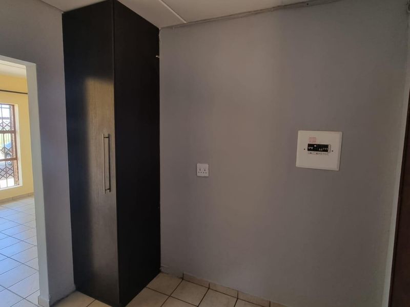 A functional utility space featuring a built-in cupboard, electrical distribution board, and ceramic tiled flooring.
