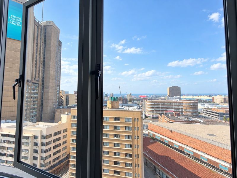 An elevated urban city view captured through a modern aluminium casement window frame.