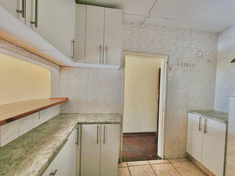A functional kitchen featuring built-in cabinetry, laminate countertops, and a pass-through window, offering a blank canvas for modern renovation and design updates.