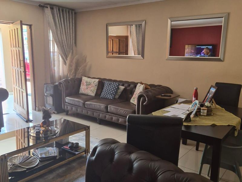 A comfortable living room featuring tiled flooring and direct access to the exterior through a timber entrance door.