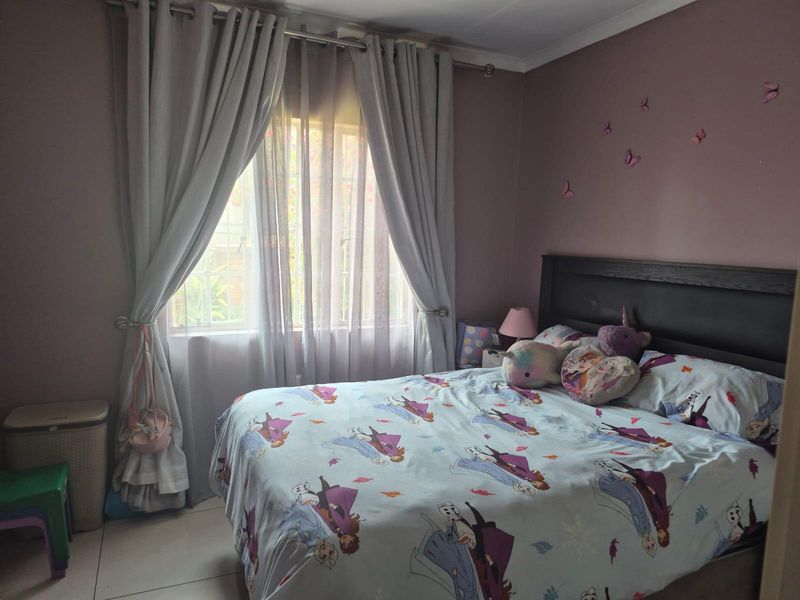 A bedroom featuring tiled flooring and a window with installed curtain rods, providing natural light.