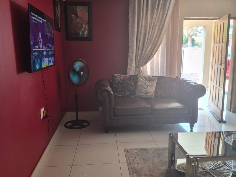 A living room featuring tiled flooring and a coved ceiling, with direct access to the exterior through a wooden door.