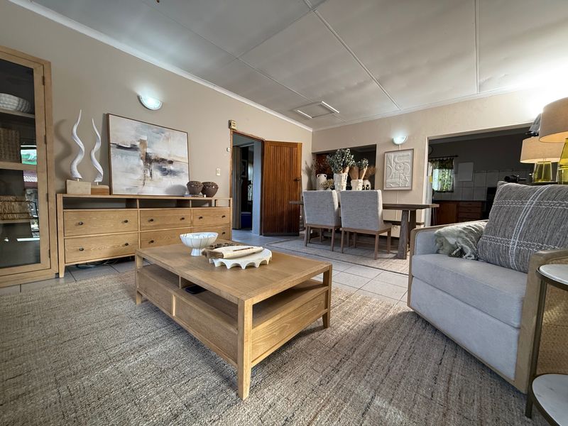 Spacious open-plan living and dining area featuring tiled flooring, neutral wall tones, and direct access to adjacent rooms.
