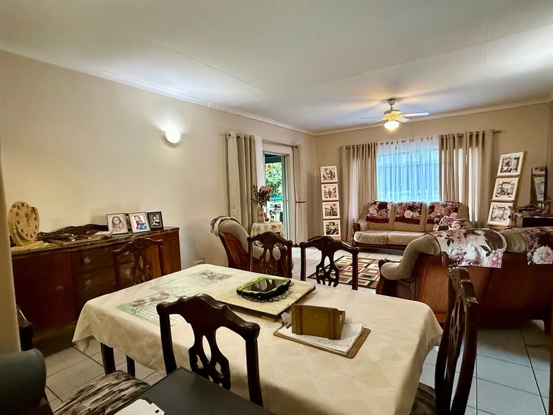 Spacious open-plan living and dining area featuring tiled flooring, a ceiling fan, and direct access to the outdoor space through a sliding glass door.