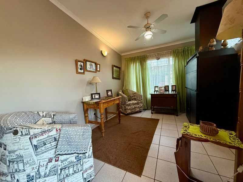A cozy living room featuring tiled flooring, a ceiling fan, and a built-in fireplace, offering a comfortable and functional living space.