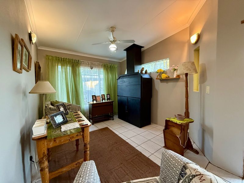 A cozy living room featuring tiled flooring, a prominent built-in fireplace, and a ceiling fan, offering a comfortable and functional living space.