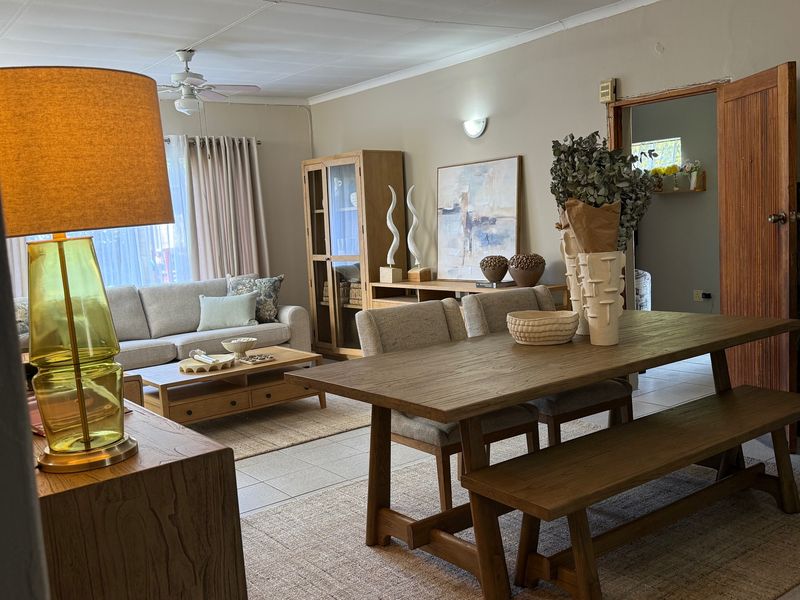 An open-plan living and dining area featuring tiled flooring, a ceiling fan, and neutral wall tones, providing a functional and connected living space.