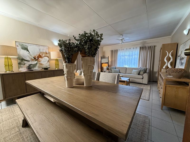 Spacious open-plan living and dining area featuring tiled flooring, a ceiling fan, and neutral finishes, offering a comfortable and versatile layout for daily living.