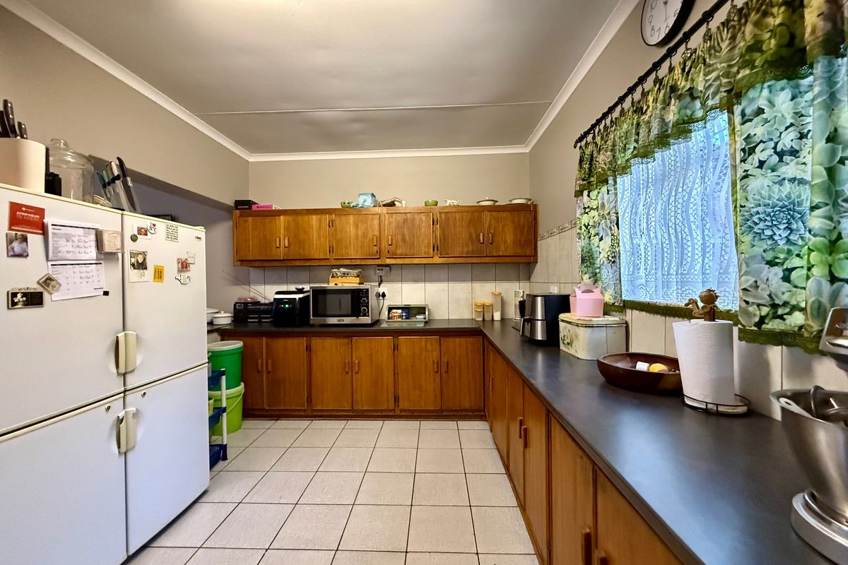 A functional kitchen featuring traditional wooden cabinetry, ample laminate counter space, and tiled flooring, offering a classic layout ready for modern updates.