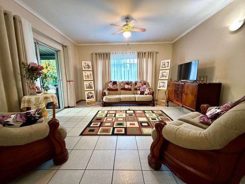 Spacious living room featuring tiled flooring, a ceiling fan, and large sliding glass doors providing access to the outdoor area.