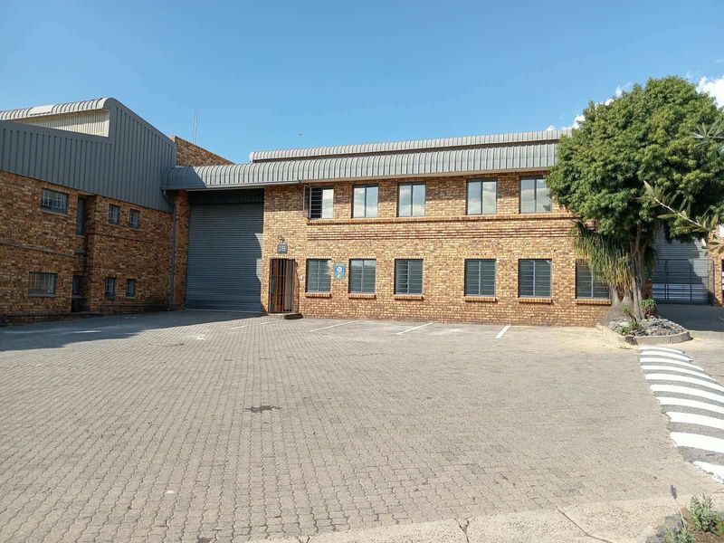 Industrial property featuring a face brick facade, roller shutter door, and paved parking area, suitable for warehouse or light industrial operations.