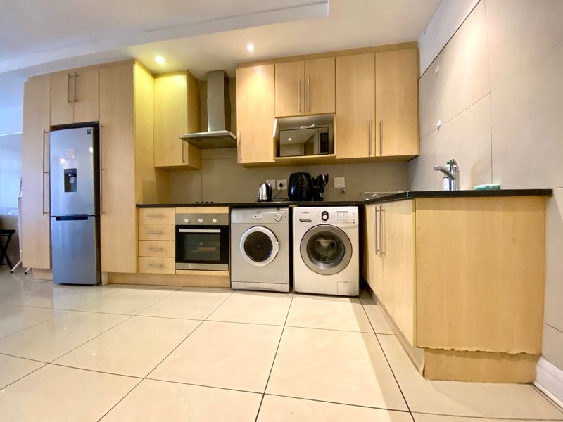 Modern kitchen featuring light wood cabinetry, granite countertops, integrated stainless steel appliances, and tiled flooring with recessed lighting.