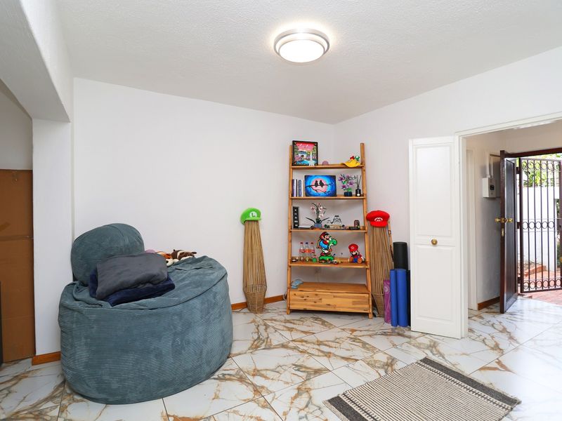 A living area featuring marble-look tiled flooring, a flush mount ceiling light, and direct access to an exterior security gate.