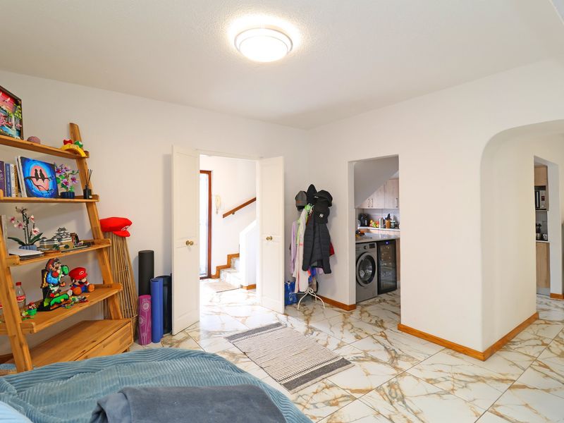 Open plan living area featuring marble-look floor tiles, an arched entryway, and double doors leading to the staircase.