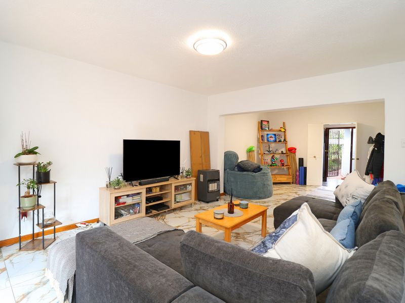 A spacious living room featuring tiled flooring and direct access to an outdoor area, offering a versatile layout for comfortable family living.