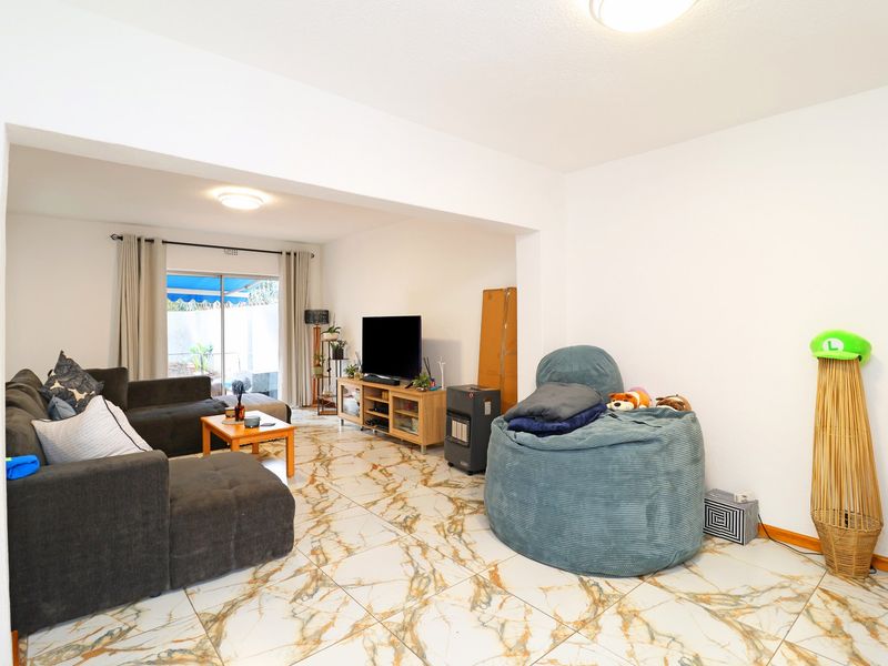 Spacious living area featuring marble-look tiled flooring and a sliding glass door providing access to the outdoor space.