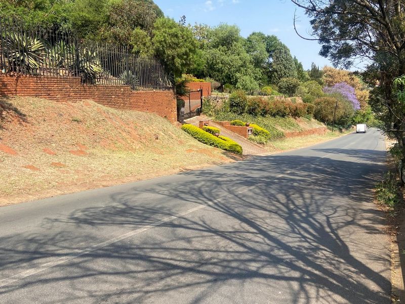 Street view of the property frontage featuring a brick retaining wall, established garden landscaping, and secure metal fencing along the boundary.