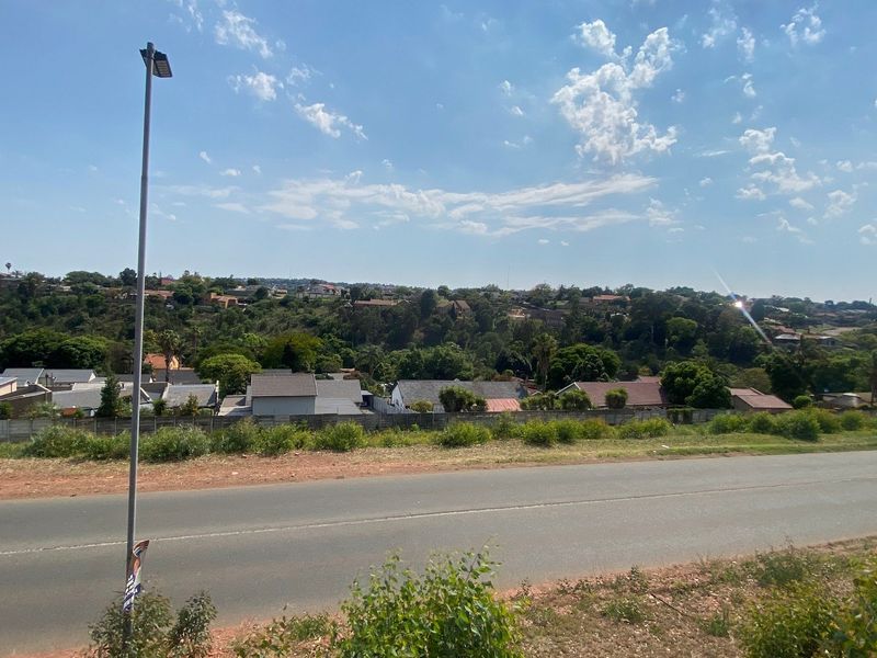 A wide-angle view overlooking a residential neighborhood and surrounding landscape from the vacant land plot.