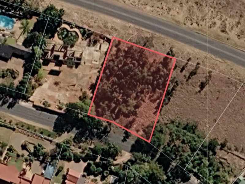 An aerial view of a vacant residential plot of land, showing its boundaries and surrounding vegetation.