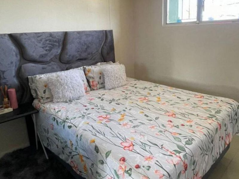 A standard bedroom featuring tiled flooring and a window fitted with security bars.