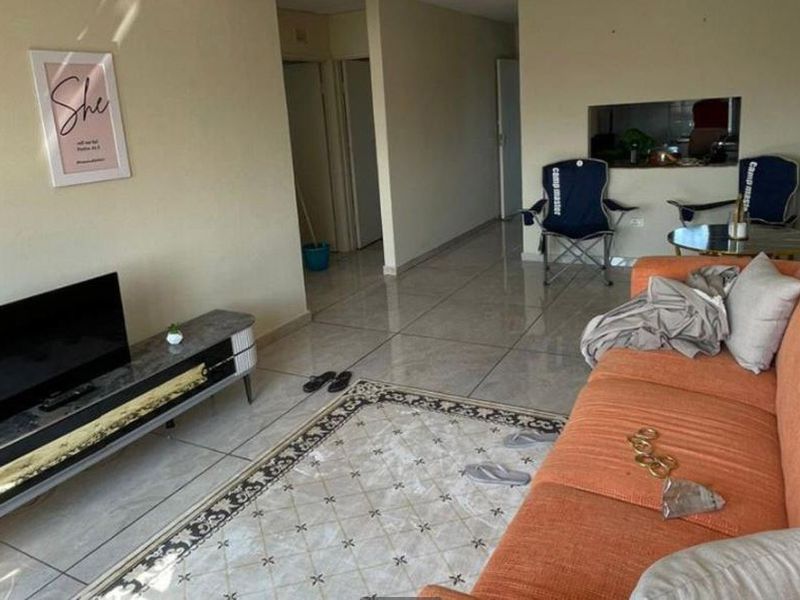 A living room area featuring tiled flooring and a convenient pass-through window connecting to the kitchen space.