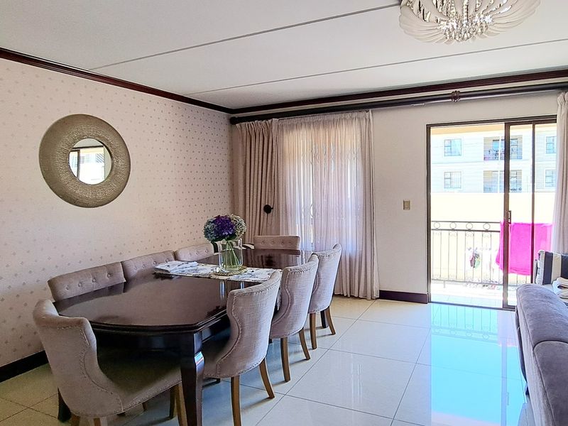 Open plan living and dining area featuring tiled flooring, crown molding, and direct access to a balcony through sliding glass doors.