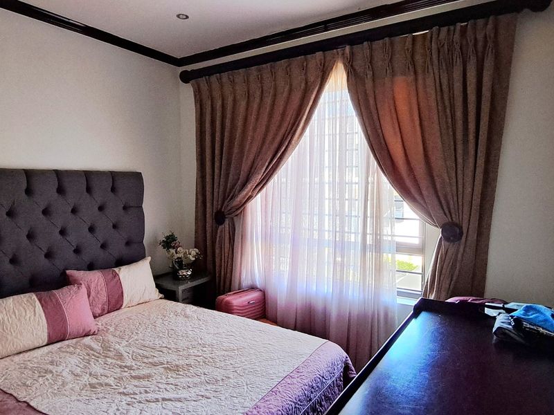 A well-maintained bedroom featuring recessed downlighting, crown molding, and a large window with fitted curtains.