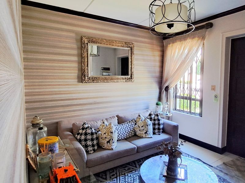 A cozy living room featuring a decorative accent wall, a security gate on the window, and a stylish pendant light fixture.