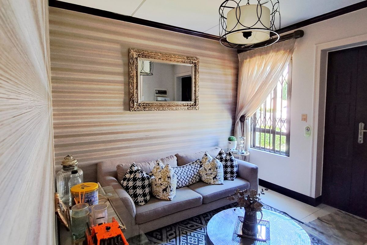 A cozy living room featuring a decorative accent wall, a security gate on the window, and a stylish pendant light fixture.