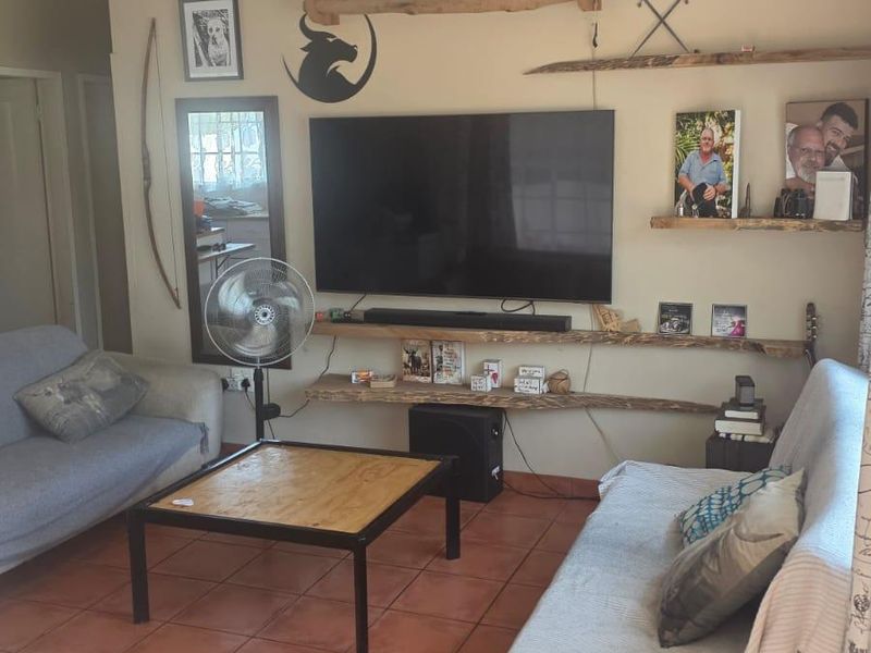 A living room featuring tiled flooring and custom built-in wooden shelving units mounted on the wall.