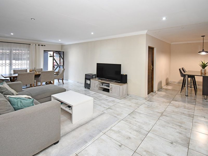 Spacious open-plan living and dining area featuring modern tiled flooring, recessed downlighting, and neutral wall finishes, providing a bright and versatile living space.