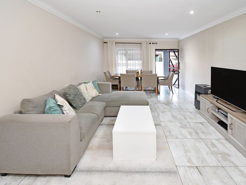 Spacious open-plan living and dining area featuring neutral wall tones, tiled flooring, and recessed lighting, providing a bright and functional layout.