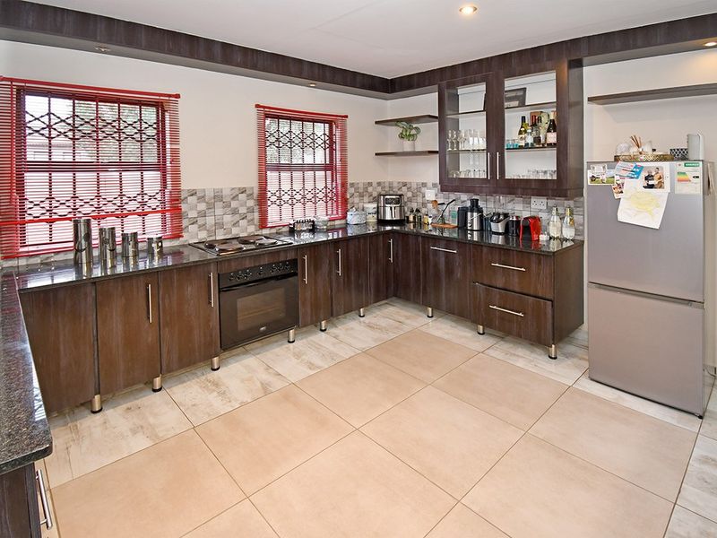 A well-maintained kitchen featuring dark wood cabinetry, granite countertops, built-in oven and hob, tiled flooring, and a decorative tiled backsplash.