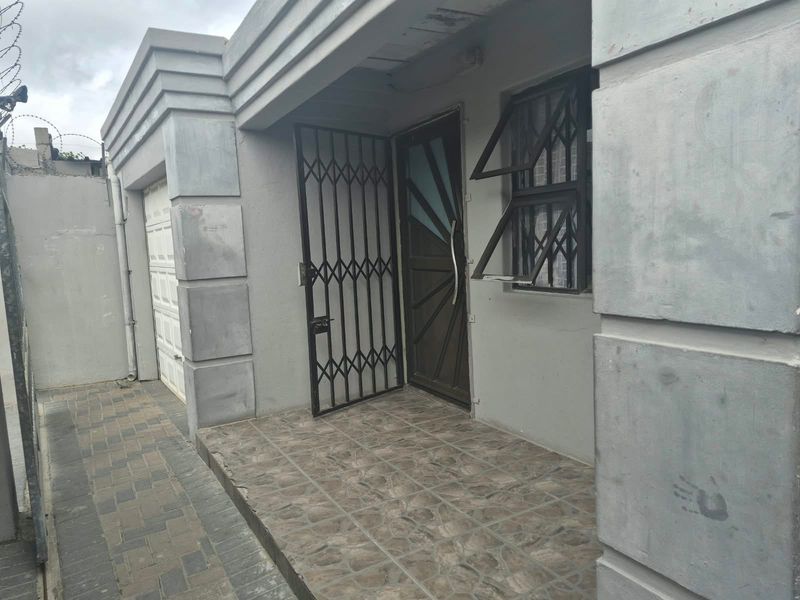 Front entrance area featuring a tiled porch, security gate, and integrated garage access with paved driveway.