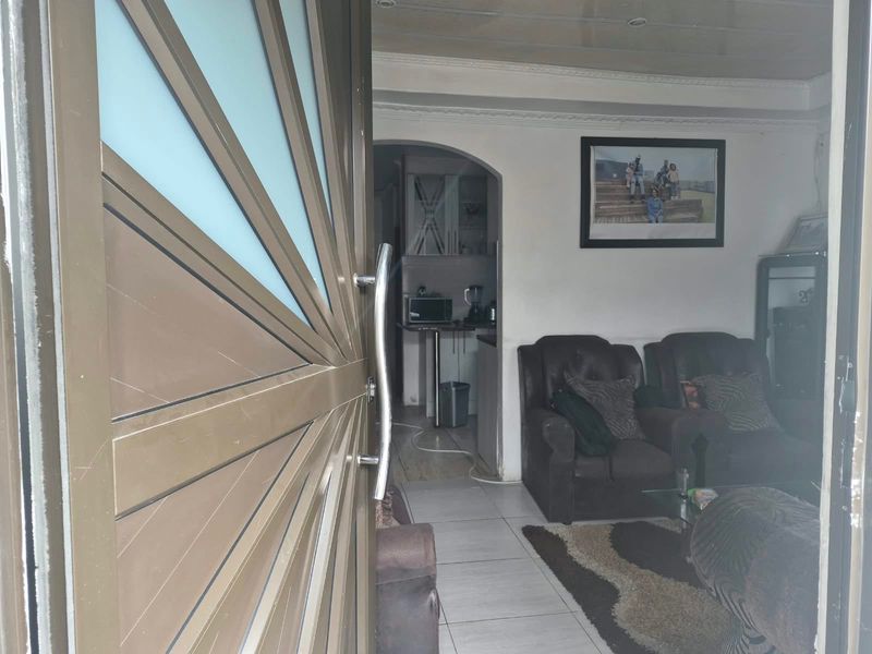 View from the front entrance into the living area, featuring tiled flooring, decorative ceiling molding, and an arched transition to the kitchen area.