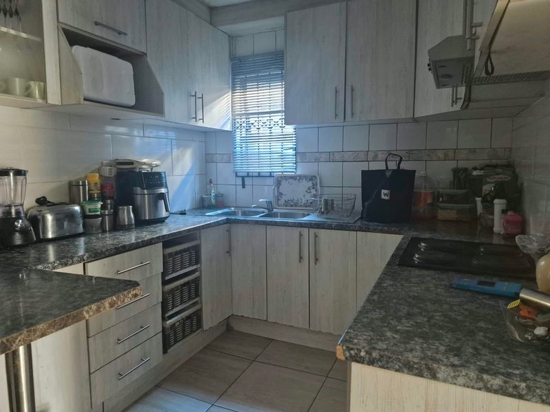 A functional kitchen featuring laminate cabinetry, granite-look countertops, a double basin sink, and a built-in hob with an extractor fan.
