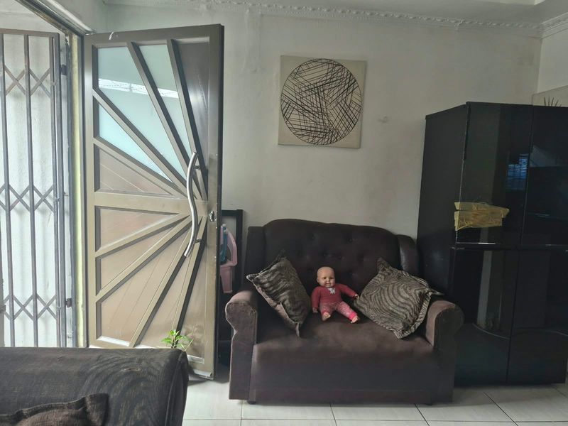 Living area featuring tiled flooring, decorative ceiling cornice, and a modern feature door with an integrated security gate.