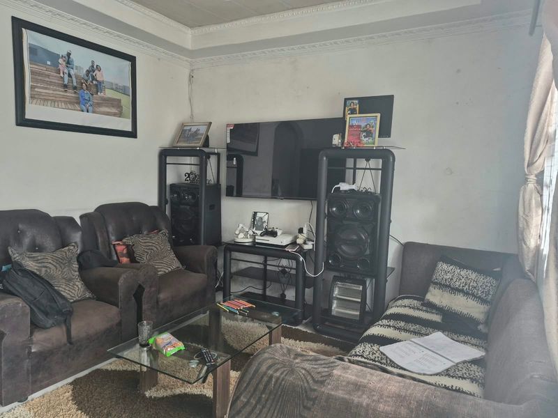 A living room featuring decorative ceiling cornicing and wall surfaces requiring maintenance and repainting.