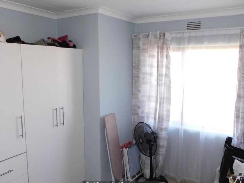 A bedroom featuring a built-in wardrobe and a window with natural light, providing a functional space for rest.