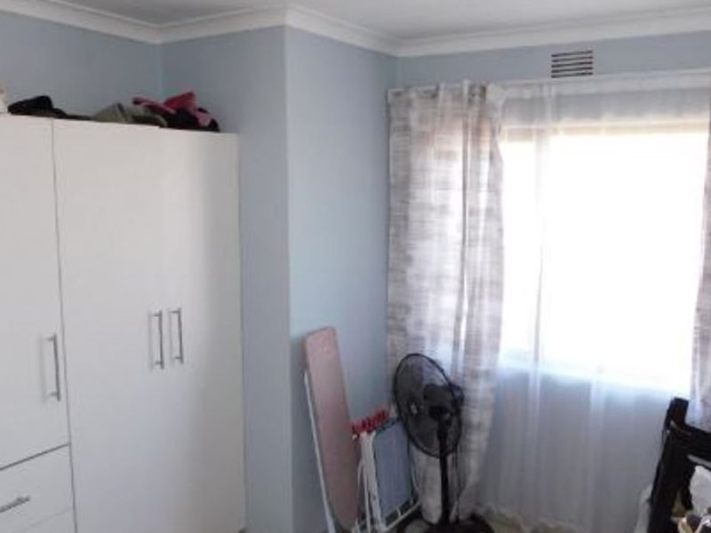 A bedroom featuring a built-in wardrobe, decorative cornice, and a window with natural light.