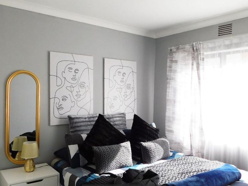 A well-maintained bedroom featuring neutral grey walls, coving, and a window with natural light.