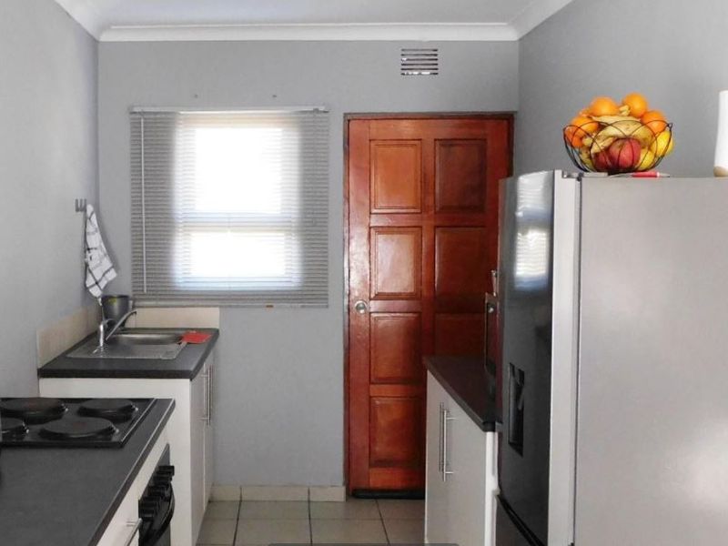 A functional kitchen featuring built-in cabinetry, laminate countertops, a stainless steel sink, and an integrated electric hob and oven.